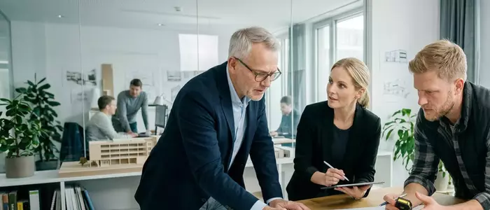 Drei Personen diskutieren über einem Plan