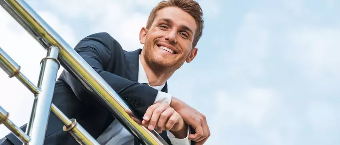 Mann lehnt lächelnd am Balkongitter