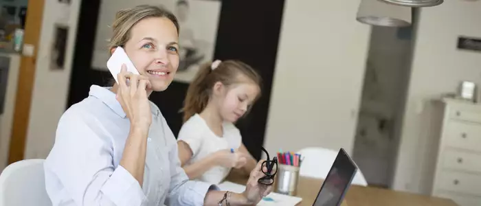 Frau im HomeOffice am Küchentisch mit Ihrer Tochter 